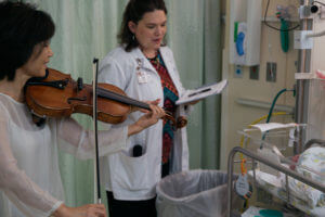 Violinist playing music for baby in hospital